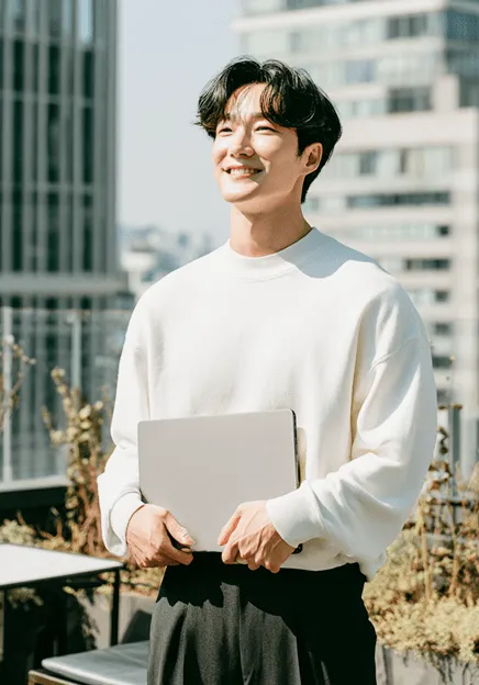 ノートパソコンを両手で持って空を見上げている若い男性